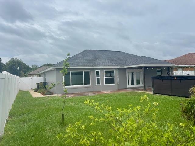 7144 Remington Oaks Loop, Lakeland, FL 33810 - rear view of house with french doors, stucco siding, a gate, and roof with shingles