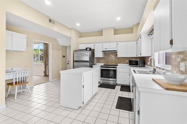 18219 Bittern Ave, Lutz, FL 33558 - kitchen with appliances with stainless steel finishes, under cabinet range hood, tasteful backsplash, a center island, and light tile patterned flooring