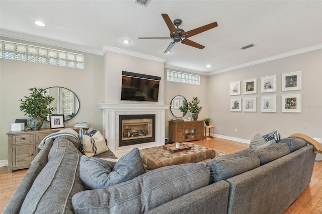 2522 W Watrous Ave, Tampa, FL 33629 - living area featuring ceiling fan, light wood-style flooring, baseboards, a tiled fireplace, and crown molding