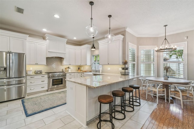 2522 W Watrous Ave, Tampa, FL 33629 - kitchen with stainless steel appliances, a peninsula, white cabinetry, light stone counters, and backsplash
