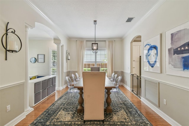 2522 W Watrous Ave, Tampa, FL 33629 - dining room featuring arched walkways, wood finished floors, crown molding, a textured ceiling, and ornate columns