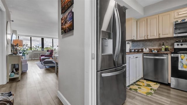 2616 Cove Cay Dr Unit 505, Clearwater, FL 33760 - kitchen featuring appliances with stainless steel finishes, cream cabinets, tasteful backsplash, light wood-type flooring, and dark stone countertops
