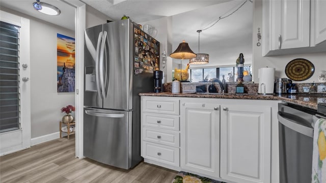 2616 Cove Cay Dr Unit 505, Clearwater, FL 33760 - kitchen with appliances with stainless steel finishes, white cabinetry, light wood-style flooring, and dark stone counters