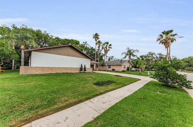 1558 Cottonwood Ter, Dunedin, FL 34698 - view of side of home with a lawn, brick siding, and stucco siding