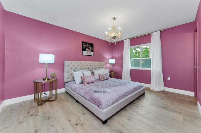 1558 Cottonwood Ter, Dunedin, FL 34698 - bedroom with wood finished floors, a chandelier, and baseboards