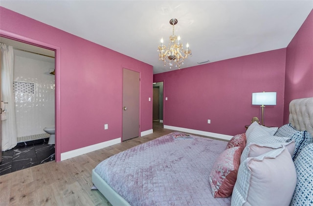 1558 Cottonwood Ter, Dunedin, FL 34698 - bedroom featuring a chandelier, wood finished floors, baseboards, and connected bathroom