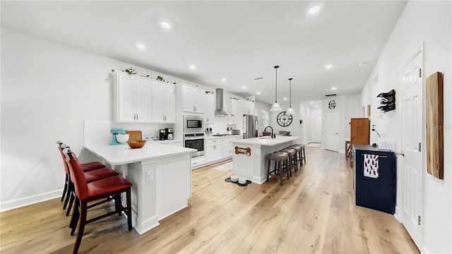 5645 Del Coronado Dr, Apollo Beach, FL 33572 - kitchen with appliances with stainless steel finishes, wall chimney range hood, a kitchen bar, a sink, and light countertops