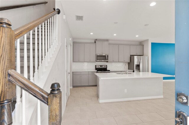 6711 Rocky Park St, Tampa, FL 33625 - kitchen featuring stainless steel appliances, gray cabinetry, a sink, light tile patterned flooring, and decorative backsplash