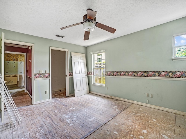 14808 Lake Magdalene Cir, Tampa, FL 33613 - unfurnished bedroom with a textured ceiling, multiple windows, baseboards, a ceiling fan, and connected bathroom