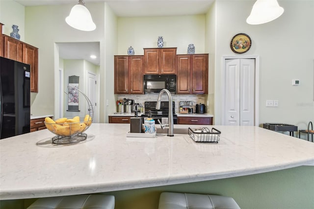 14206 Covert Green Pl, Riverview, FL 33579 - kitchen with black appliances, a kitchen breakfast bar, pendant lighting, backsplash, and light stone countertops