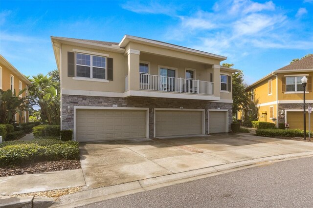7001 Interbay Blvd Unit 242, Tampa, FL 33616 - view of front of home with concrete driveway, stucco siding, a garage, stone siding, and a balcony