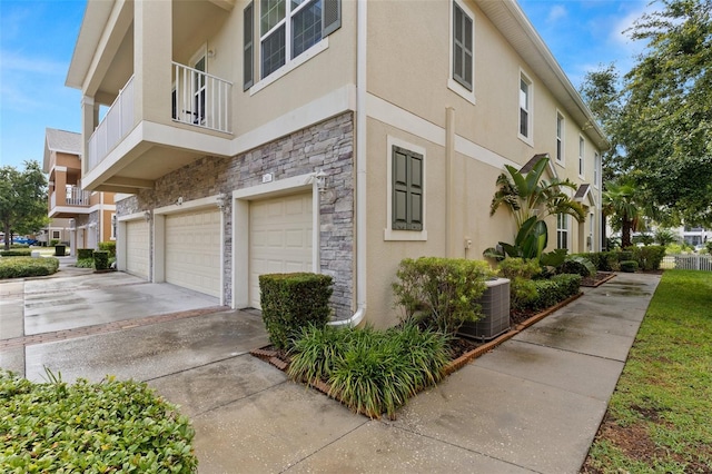 7001 Interbay Blvd Unit 242, Tampa, FL 33616 - view of side of property with stone siding, stucco siding, an attached garage, concrete driveway, and central air condition unit