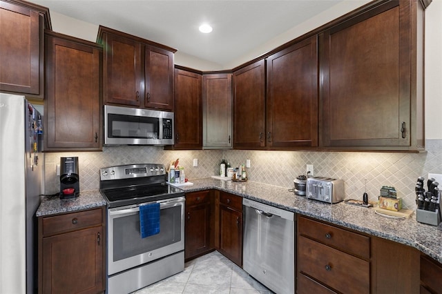 7001 Interbay Blvd Unit 242, Tampa, FL 33616 - kitchen with stainless steel appliances, dark stone counters, dark brown cabinetry, and tasteful backsplash