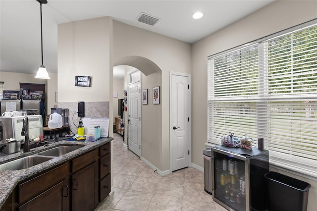 7001 Interbay Blvd Unit 242, Tampa, FL 33616 - kitchen featuring a sink, arched walkways, dark brown cabinetry, dark stone counters, and light tile patterned floors