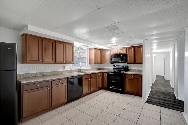 7524 Tidewater Trl, Tampa, FL 33619 - kitchen with black appliances, a sink, brown cabinetry, light countertops, and a drop ceiling