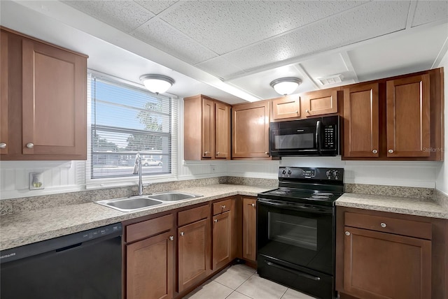 7524 Tidewater Trl, Tampa, FL 33619 - kitchen featuring black appliances, a sink, light countertops, light tile patterned floors, and brown cabinets
