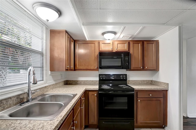 7524 Tidewater Trl, Tampa, FL 33619 - kitchen with black appliances, a sink, light countertops, and brown cabinetry