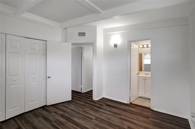 7524 Tidewater Trl, Tampa, FL 33619 - unfurnished bedroom with beamed ceiling, dark wood-style flooring, a closet, connected bathroom, and baseboards