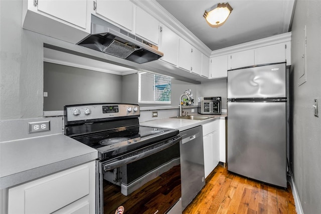 1301 S Howard Ave Unit A22, Tampa, FL 33606 - kitchen with appliances with stainless steel finishes, a sink, under cabinet range hood, light wood-type flooring, and light countertops