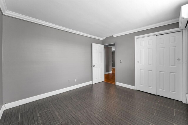 1301 S Howard Ave Unit A22, Tampa, FL 33606 - unfurnished bedroom with crown molding, baseboards, a wall mounted AC, dark wood-style flooring, and a closet