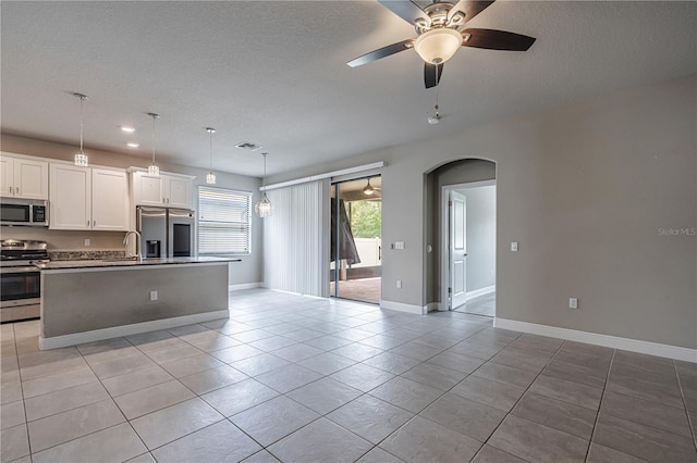19974 Bluebird Meadow Dr, Lutz, FL 33558 - kitchen with stainless steel appliances, arched walkways, ceiling fan, a textured ceiling, and an island with sink