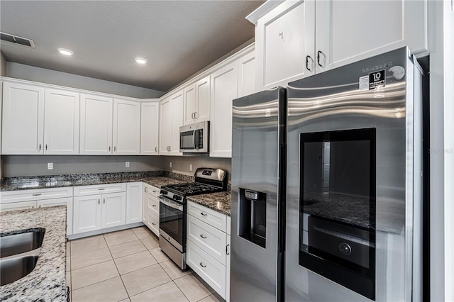 19974 Bluebird Meadow Dr, Lutz, FL 33558 - kitchen with appliances with stainless steel finishes, white cabinets, light tile patterned flooring, dark stone counters, and recessed lighting