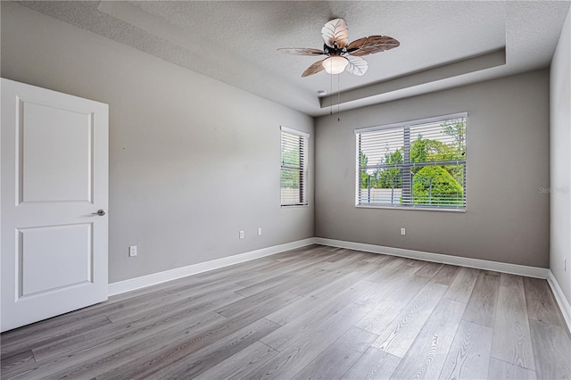 19974 Bluebird Meadow Dr, Lutz, FL 33558 - unfurnished room with a textured ceiling, light wood-style floors, a ceiling fan, and a tray ceiling