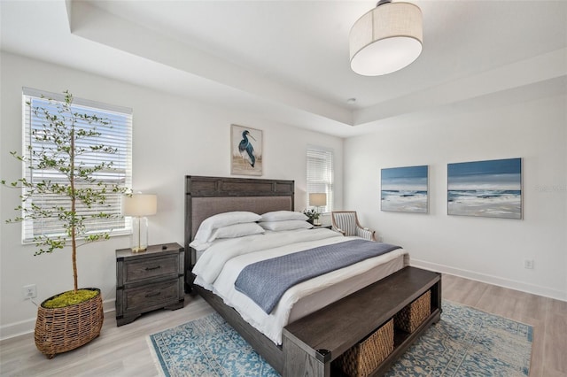 32490 Tree Of Life Ave, Wesley Chapel, FL 33543 - bedroom featuring a raised ceiling, light wood-style floors, and baseboards