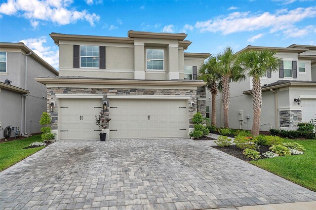 32490 Tree Of Life Ave, Wesley Chapel, FL 33543 - view of front of home featuring a garage, decorative driveway, stucco siding, and stone siding