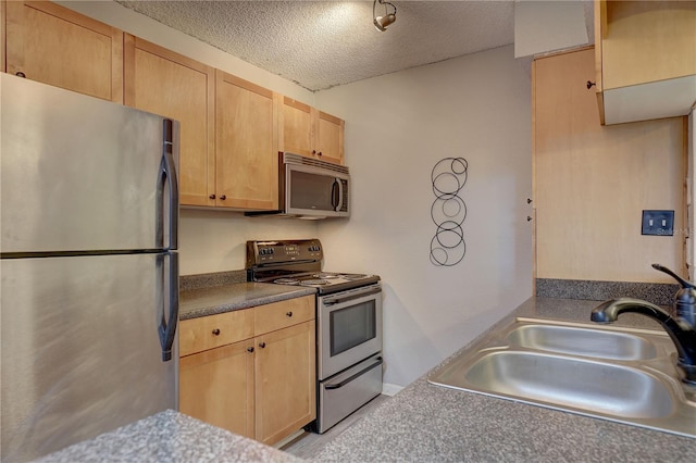 2500 Winding Creek Blvd Unit G307, Clearwater, FL 33761 - kitchen featuring appliances with stainless steel finishes, a sink, a textured ceiling, light brown cabinetry, and dark countertops