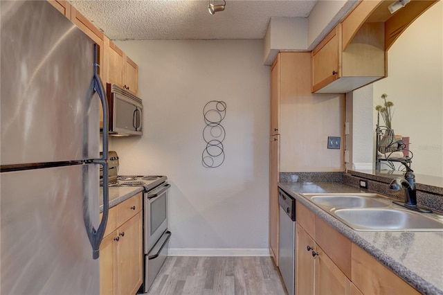 2500 Winding Creek Blvd Unit G307, Clearwater, FL 33761 - kitchen with appliances with stainless steel finishes, light brown cabinetry, light wood-style floors, a sink, and a textured ceiling