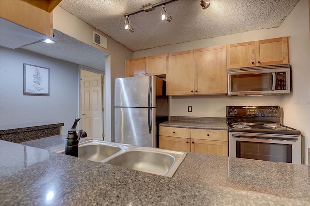 2500 Winding Creek Blvd Unit G307, Clearwater, FL 33761 - kitchen with appliances with stainless steel finishes, a sink, light brown cabinets, a textured ceiling, and dark countertops