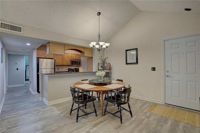2500 Winding Creek Blvd Unit G307, Clearwater, FL 33761 - dining area featuring light wood finished floors, a chandelier, vaulted ceiling, baseboards, and a textured ceiling