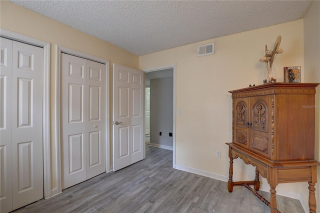 2500 Winding Creek Blvd Unit G307, Clearwater, FL 33761 - bedroom featuring light wood-type flooring, two closets, a textured ceiling, and baseboards