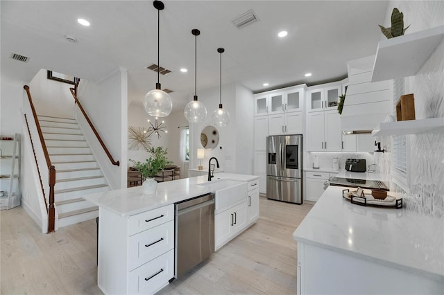 6512 Simone Shores Cir, Apollo Beach, FL 33572 - kitchen featuring stainless steel appliances, a sink, light wood-style flooring, backsplash, and a center island with sink