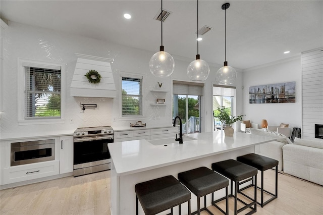 6512 Simone Shores Cir, Apollo Beach, FL 33572 - kitchen with stainless steel electric range oven, light wood-type flooring, a sink, white cabinetry, and recessed lighting