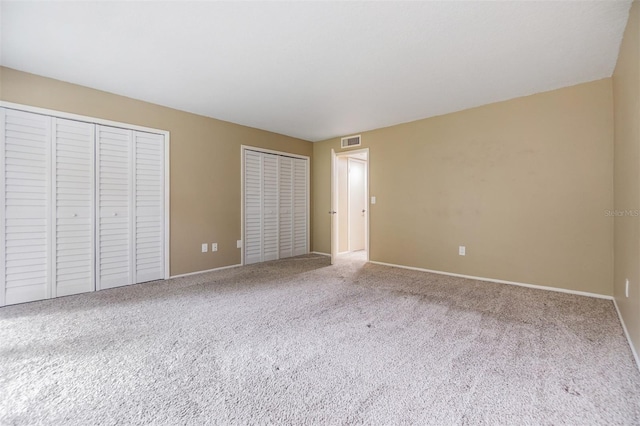 2699 Seville Blvd Unit 207, Clearwater, FL 33764 - unfurnished bedroom featuring two closets, carpet, and baseboards