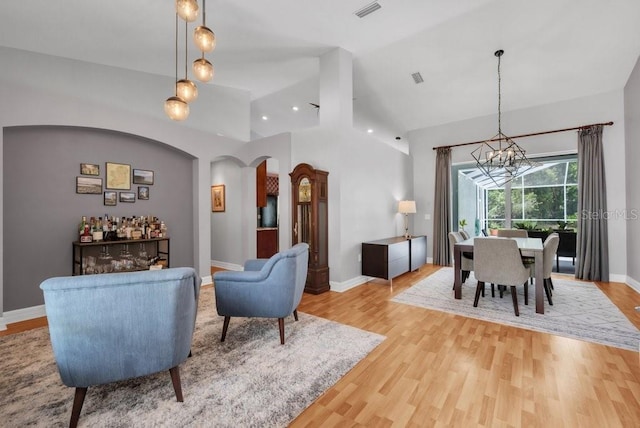 15309 Palomapark Ln, Lithia, FL 33547 - living room with a chandelier, light wood-style floors, baseboards, arched walkways, and high vaulted ceiling