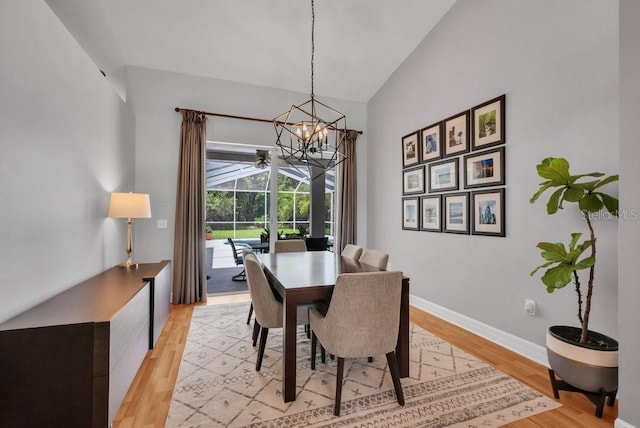15309 Palomapark Ln, Lithia, FL 33547 - dining room with a chandelier, light wood-style flooring, baseboards, and high vaulted ceiling