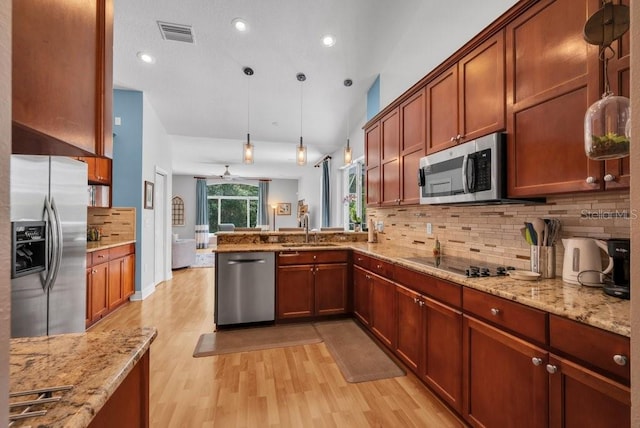 15309 Palomapark Ln, Lithia, FL 33547 - kitchen featuring appliances with stainless steel finishes, a sink, light wood finished floors, a peninsula, and decorative backsplash