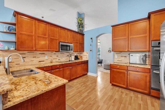 15309 Palomapark Ln, Lithia, FL 33547 - kitchen featuring a sink, stainless steel appliances, arched walkways, open shelves, and backsplash