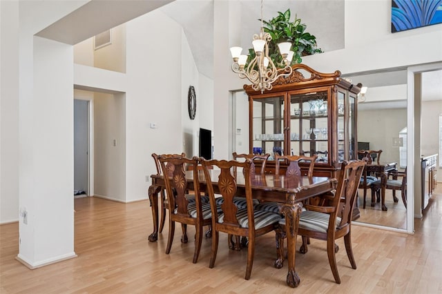 11638 Branch Mooring Dr, Tampa, FL 33635 - dining area featuring light wood-type flooring, a chandelier, a towering ceiling, and baseboards