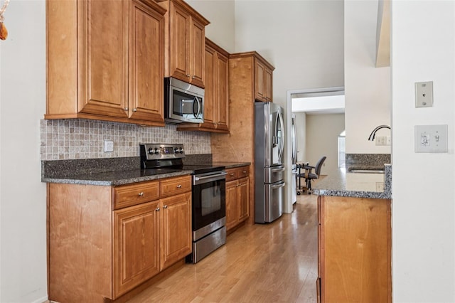 11638 Branch Mooring Dr, Tampa, FL 33635 - kitchen with stainless steel appliances, a sink, light wood-style floors, tasteful backsplash, and brown cabinets