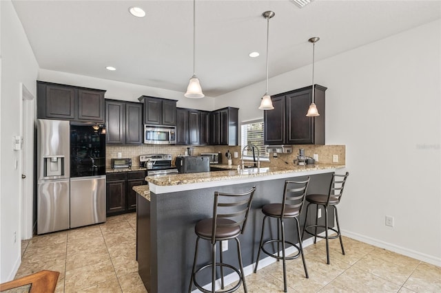 12244 Fairlawn Dr, Riverview, FL 33579 - kitchen featuring appliances with stainless steel finishes, a peninsula, tasteful backsplash, light stone counters, and a kitchen bar