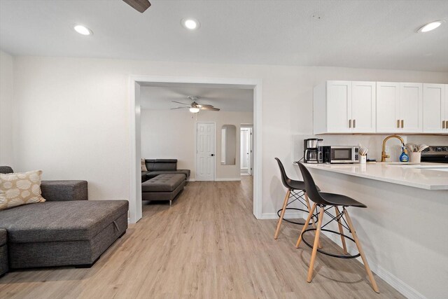 608 Bay Esplanade, Clearwater Beach, FL 33767 - kitchen with open floor plan, stainless steel microwave, light wood-style flooring, a breakfast bar area, and light countertops
