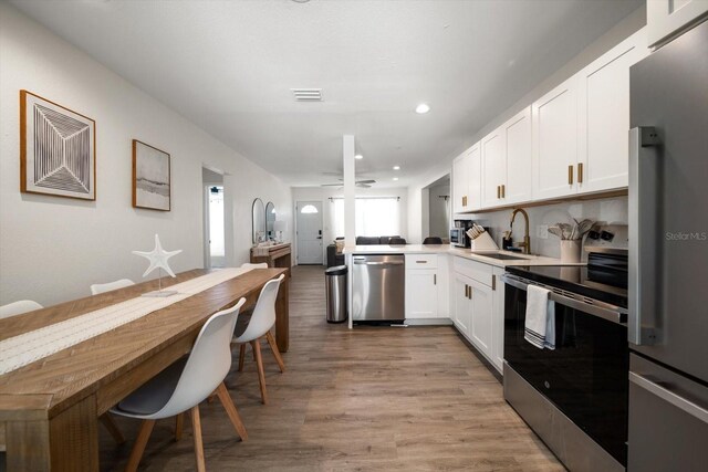 608 Bay Esplanade, Clearwater Beach, FL 33767 - kitchen featuring appliances with stainless steel finishes, white cabinets, light wood finished floors, light countertops, and recessed lighting