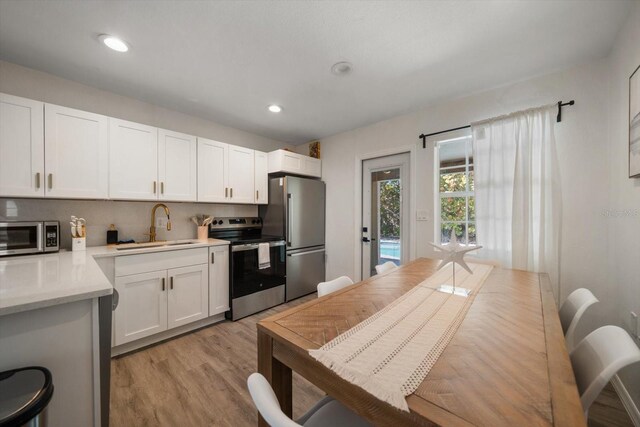608 Bay Esplanade, Clearwater Beach, FL 33767 - kitchen featuring appliances with stainless steel finishes, light wood-style floors, light countertops, white cabinetry, and recessed lighting