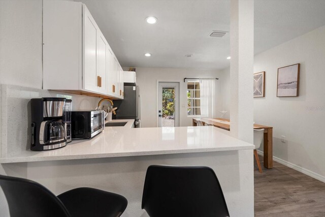 608 Bay Esplanade, Clearwater Beach, FL 33767 - kitchen featuring stainless steel appliances, white cabinetry, a peninsula, light wood-style flooring, and recessed lighting