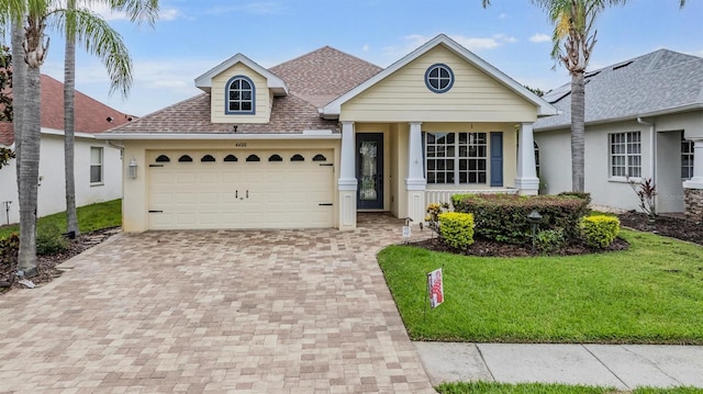 4400 English Turn Way, Wesley Chapel, FL 33543 - view of front of house featuring decorative driveway, a front yard, roof with shingles, a garage, and stucco siding