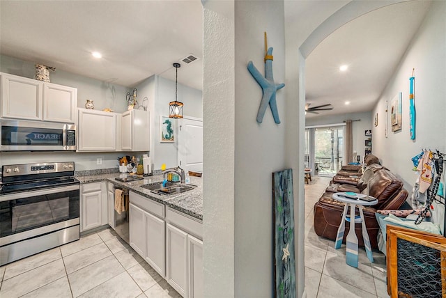 2844 Jacob Crossing Ln, Holiday, FL 34691 - kitchen with stainless steel appliances, a sink, arched walkways, light tile patterned flooring, and light stone counters
